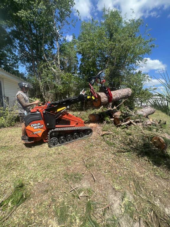 A machine called Ditch Witch removing tree debris from the backyard of a residential tree service